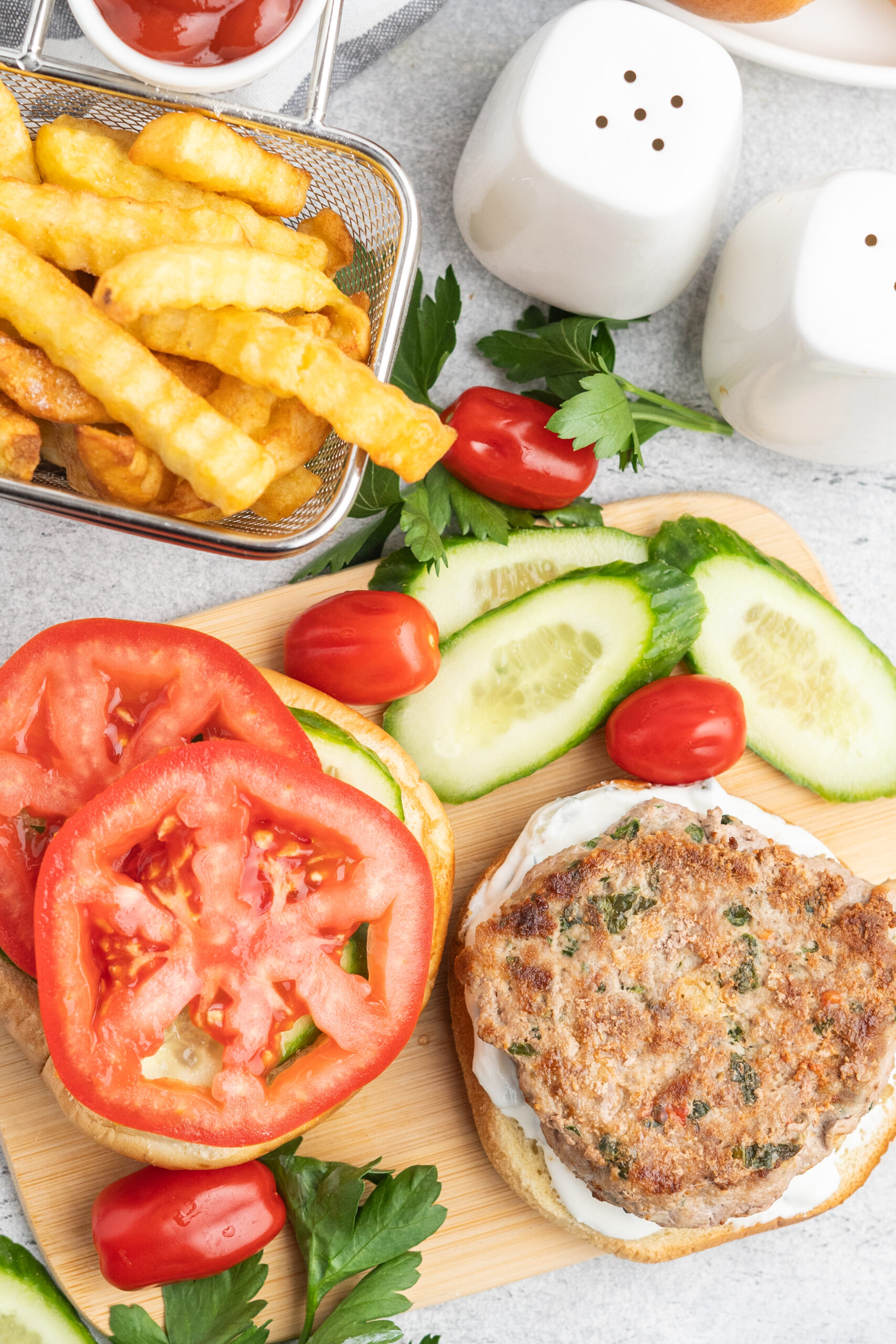 Open faced turkey burger with cucumber and tomatoes and a side of fries.