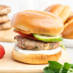 Turkey burger on a brioche bun with cucubmer and tomato.