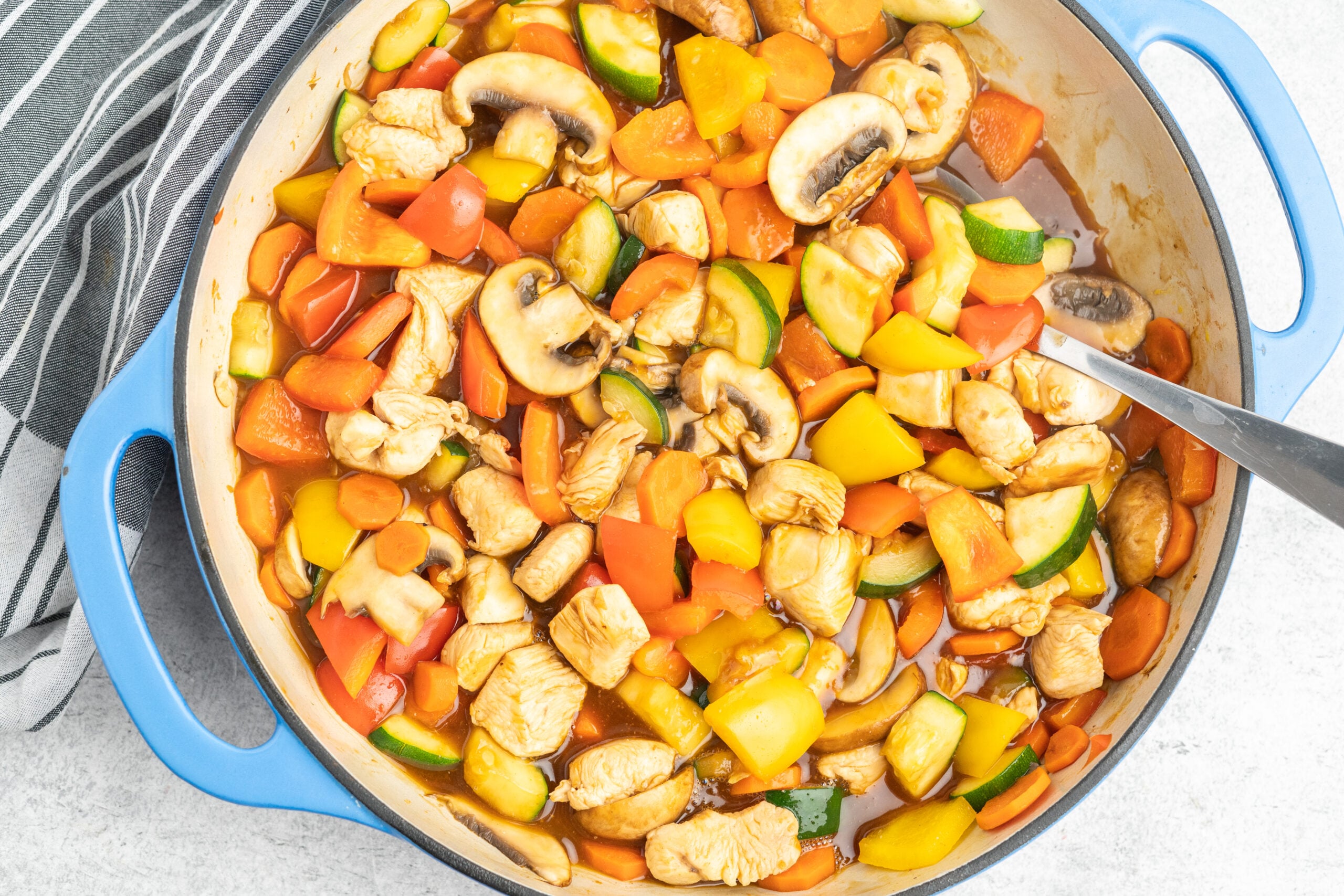 A cast iron skillet with diced vegetables and chicken in sauce.