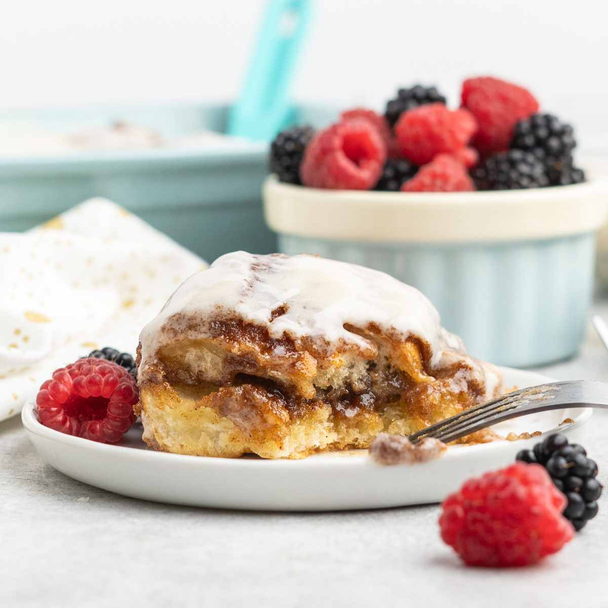 Cinnamon roll on a plate with fresh berries.