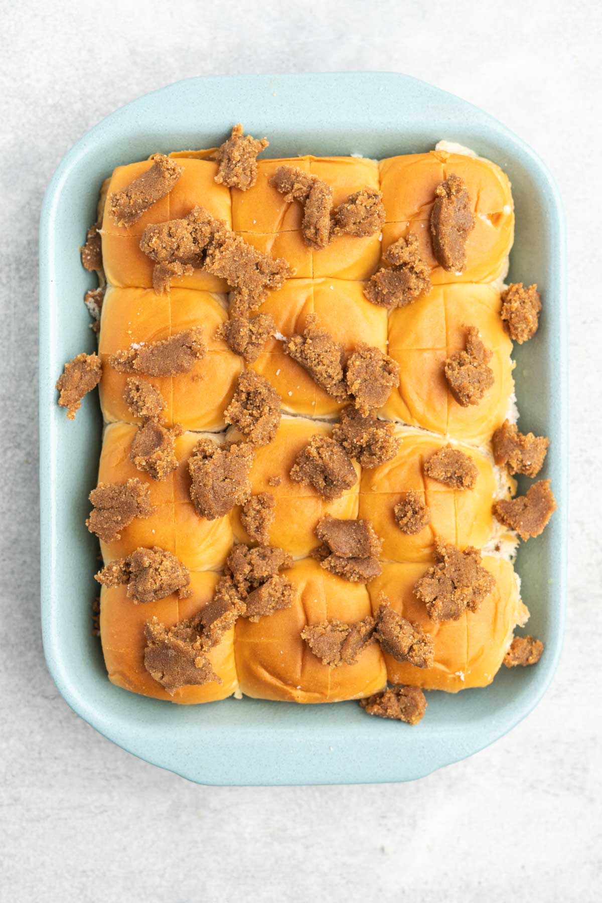 Hawaiian rolls in a baking dish, topped with dollops of cinnamon butter.