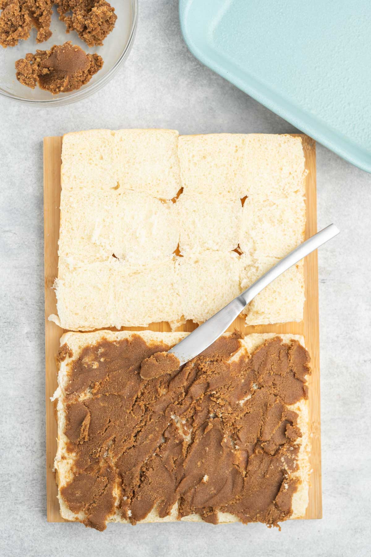 Hawaiian rolls cut in half with cinnamon butter spread on one side.