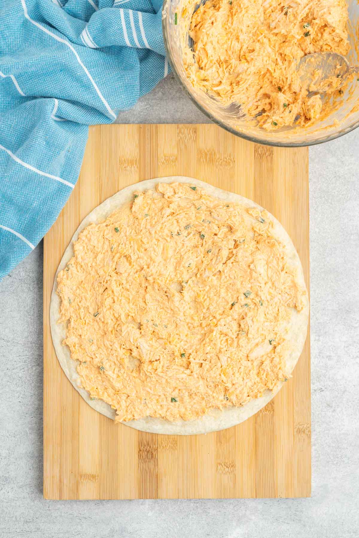 Buffalo chicken mixture spread on a tortilla. 