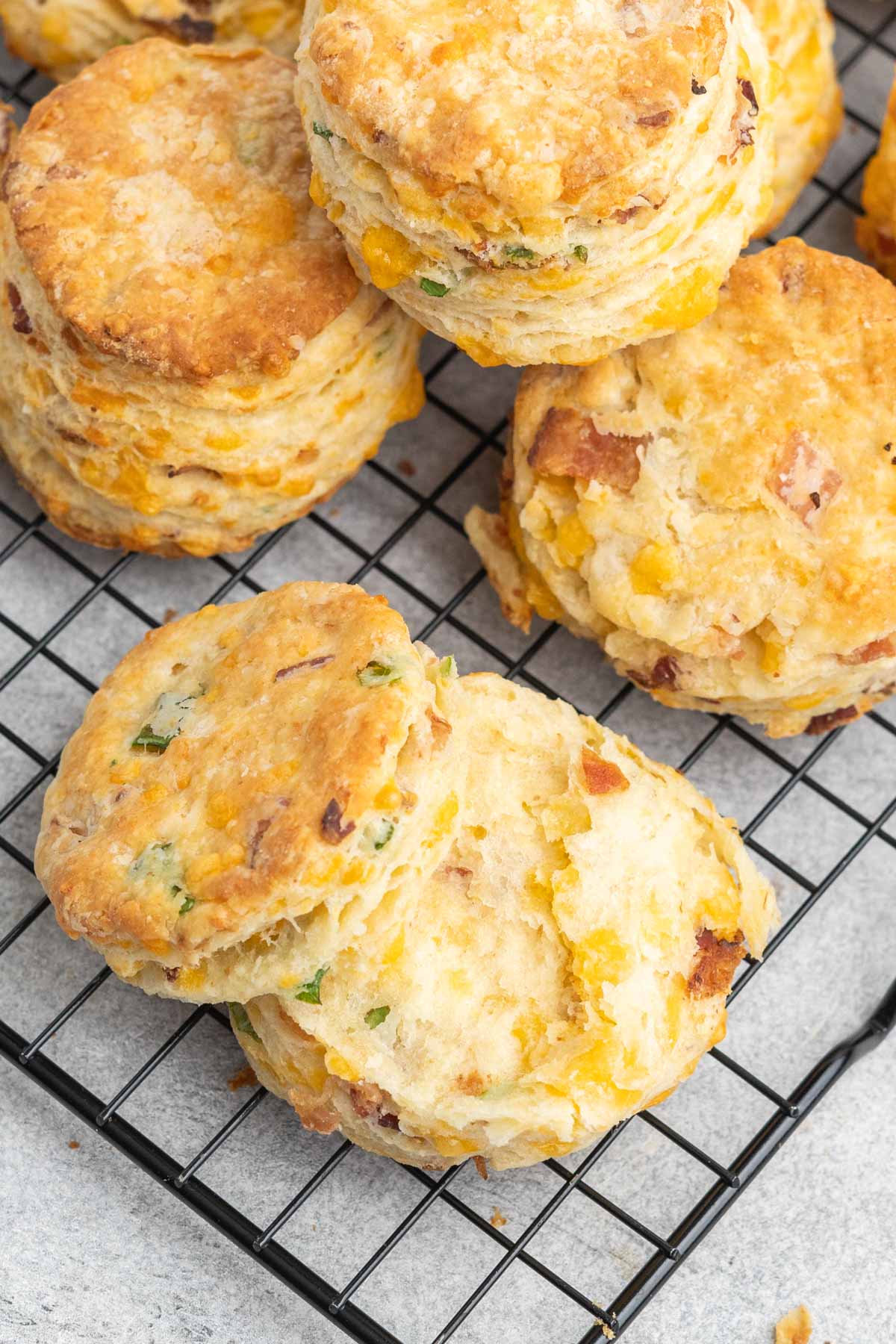 One biscuit cut in half on a cooling rack with a pile of whole biscuits.