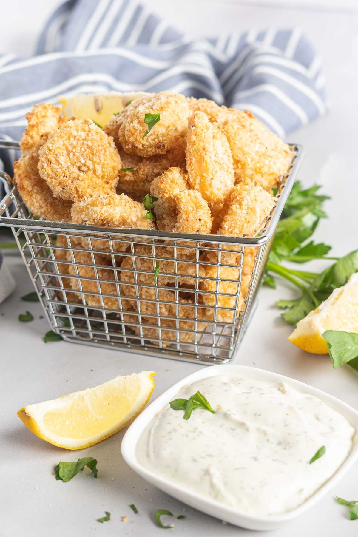 Breaded shrimp in a basket with lemon wedges and dip. 