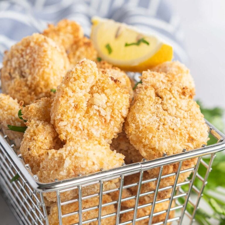 Breaded shrimp in a basket with a lemon wedge.