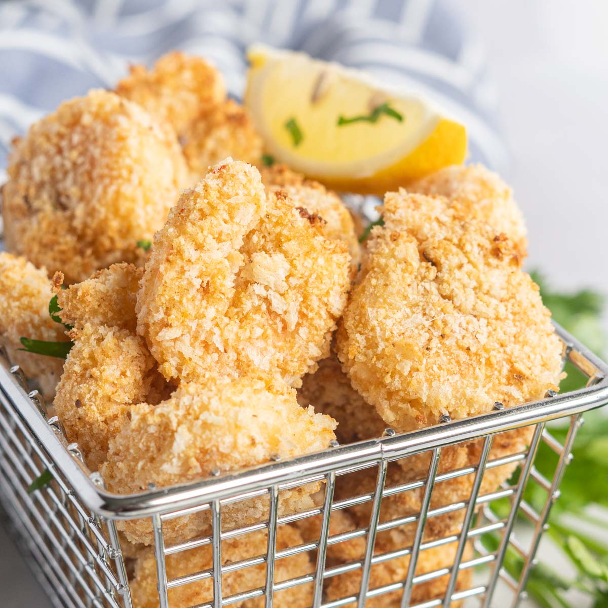 Breaded shrimp in a basket with a lemon wedge.